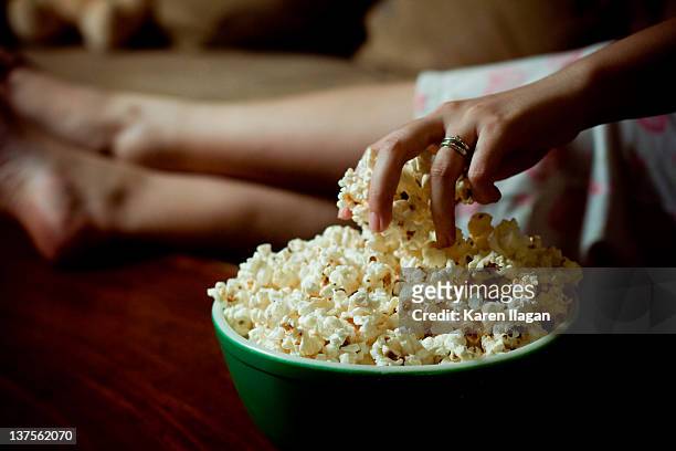 woman hand into bowl of popcorn - snack bowl stock pictures, royalty-free photos & images