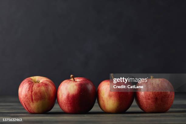 still life with apples arranged together in a row on a dark background - gala background stock pictures, royalty-free photos & images