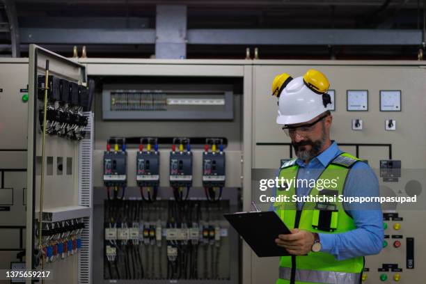 male caucasian working with digital tablet in front of the electric control panel. - fuse box ストックフォトと画像