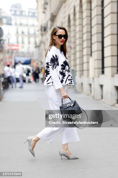 Influencer Alexandra Lapp wearing a black and white para jacket with floral print by Airfield, white anisha pants by Airfield, a black bag by Hermes,...