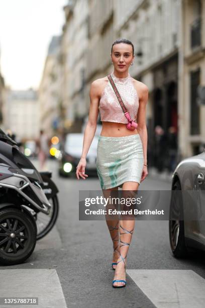 Mary Leest wears silver and diamonds earrings, a pale pink sequined halter neck cropped top, a pink matte leather micro crossbody bag from Fendi,...