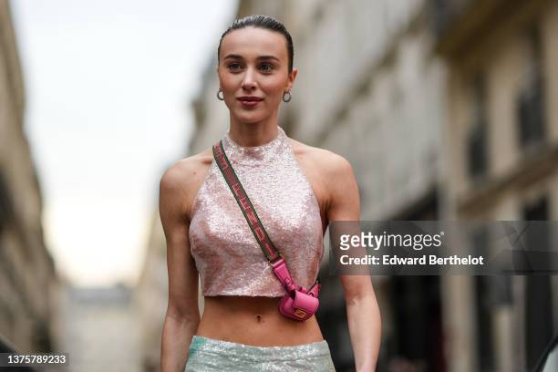 Mary Leest wears silver and diamonds earrings, a pale pink sequined halter neck cropped top, a pink matte leather micro crossbody bag from Fendi,...