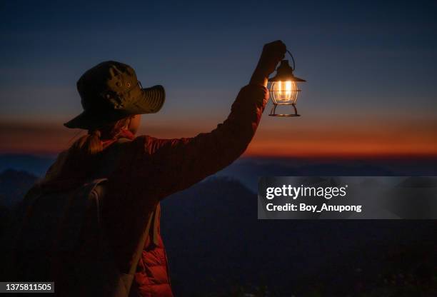 silhouette of tourist woman open an electric lantern  while looking to beautiful twilight sky of the nature at dusk. - jack o lantern foto e immagini stock