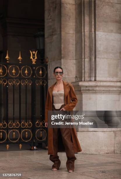 Alexandra Guerain seen wearing brown suede coat, brown leather pants, beige off shoulder top, sunglasses and a sleek bun hairstyle outside Nanushka...