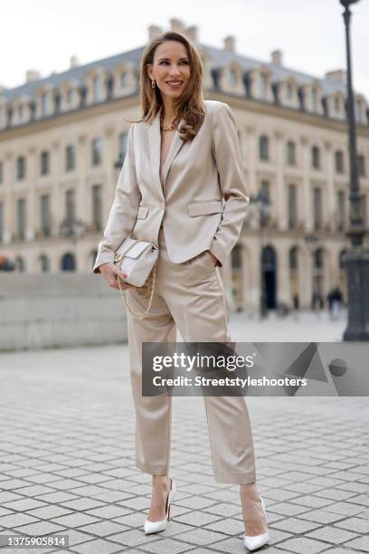 Influencer Alexandra Lapp wearing a light beige colored satin blazer and matching pants by Comma, a cream colored tank top by Comma, gold City...