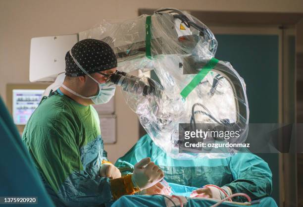 male neurosurgeon team operating brain tumor surgery in hospital operating room - robotic surgery stock pictures, royalty-free photos & images