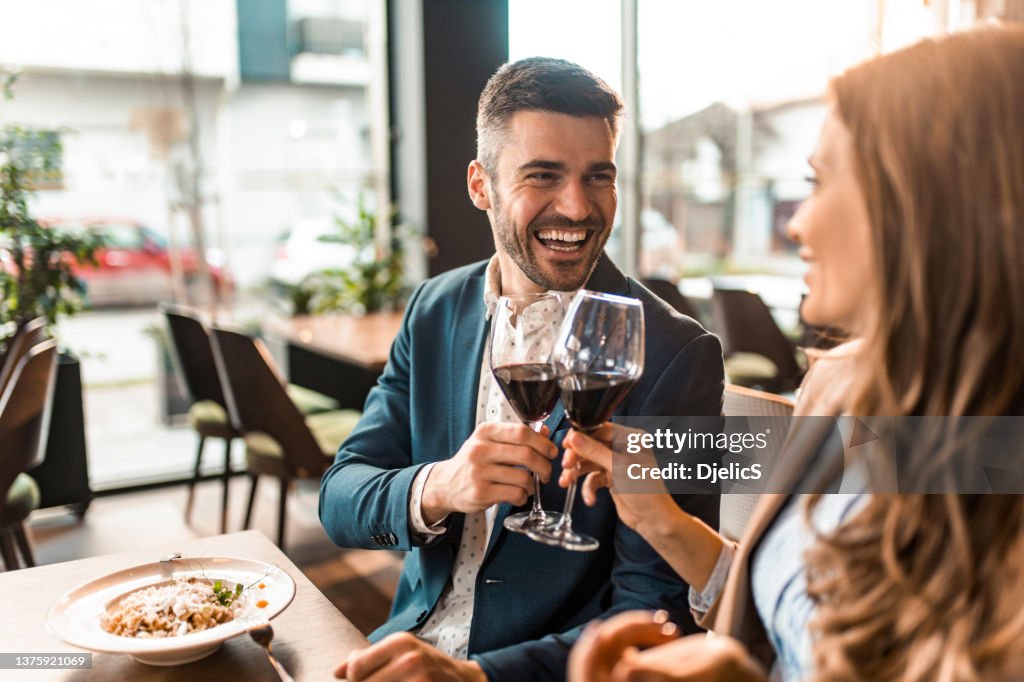 Coppia felice che pranza insieme in un ristorante e brinda con il vino.