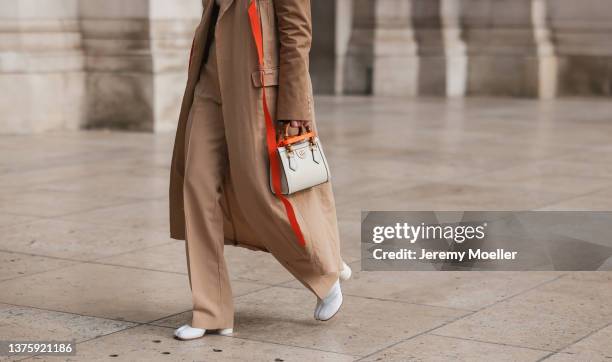 Alice Barbier seen in beige coat with orange stripes, wide beige pants, white orange gucci diana bag, cropped white top, white Maison Margiela Tabi...