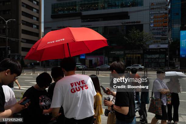 An employee assists customers waiting in line to enter the first outlet of US burger restaurant chain Five Guys in the Gangnam District of Seoul,...