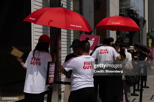 Employees assist customers waiting in line to enter the first outlet of US burger restaurant chain Five Guys in the Gangnam District of Seoul, South...
