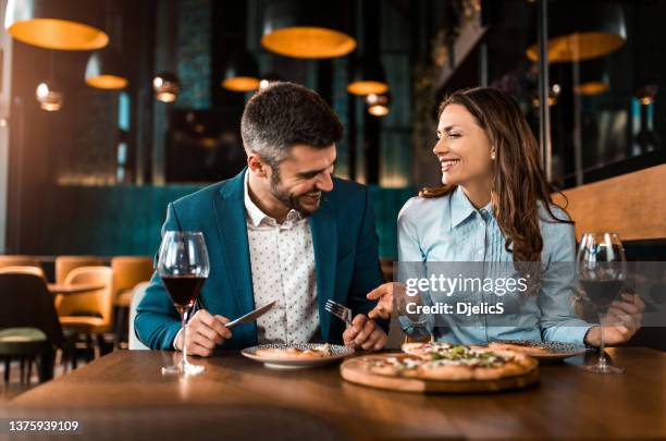 playful couple eating pizza together in a restaurant. - elegant couple stockfoto's en -beelden