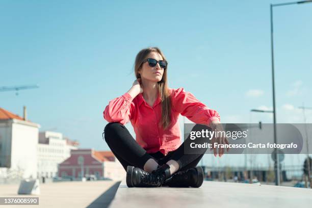 yoman sitting on a wall on sunny day - frau mit sonnenbrille stock-fotos und bilder