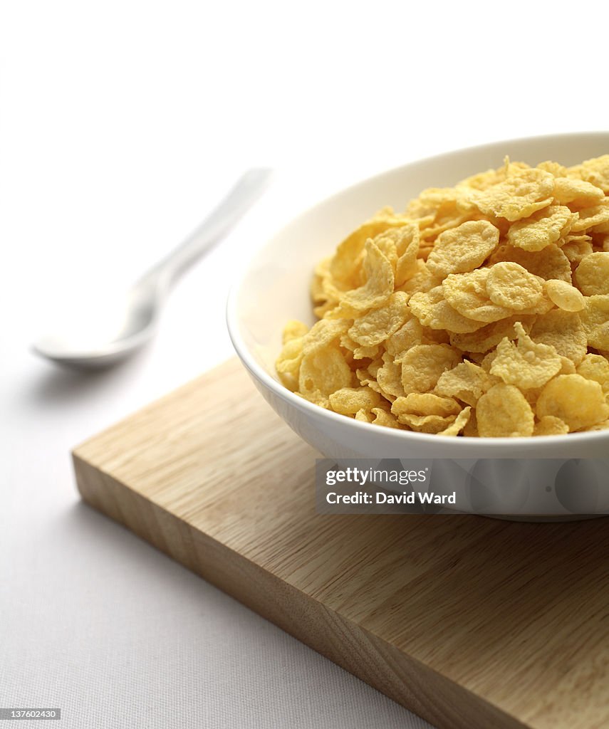 A white bowl full of cereal on a wooden board.