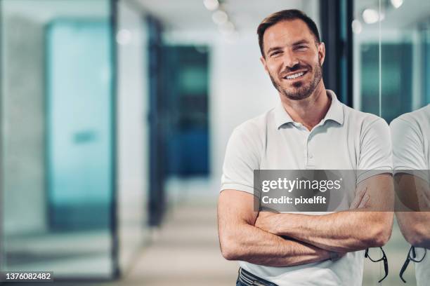 smiling middle aged man standing with arms crossed - poloshirt stockfoto's en -beelden