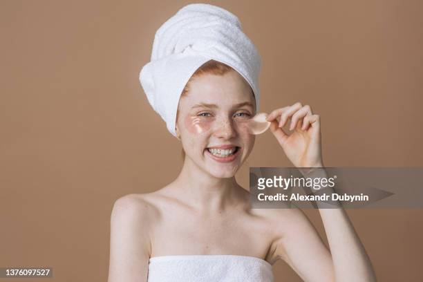 happy young caucasian woman with a natural look without makeup and a white smile, removes silicone patches under her eyes and smiles happily, using a skin care cosmetic product - face mask beauty product - fotografias e filmes do acervo