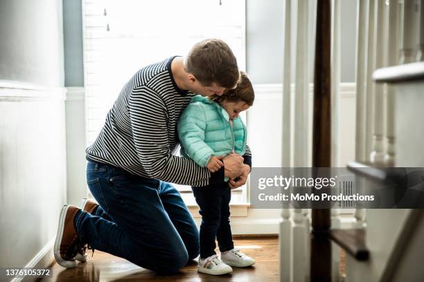 father getting daughter dressed to go outside - puffer jacket photos et images de collection