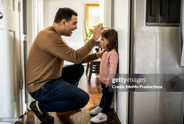 father measuring toddler daughter's height against wall - 高度表 個照片及圖片檔