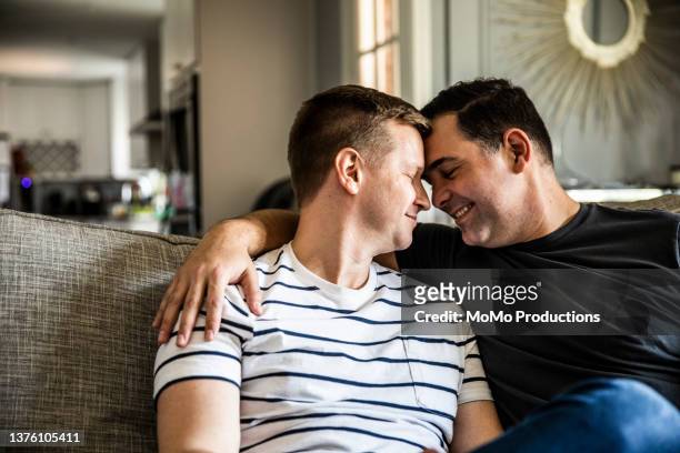 gay couple embracing on couch - psychiatrist's couch stock pictures, royalty-free photos & images