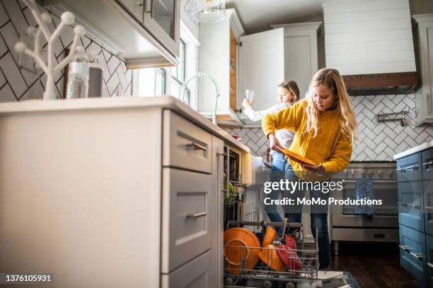 tween girls doing dishes in modern kitchen - huishoudklusjes stockfoto's en -beelden