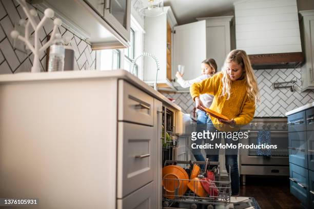 tween girls doing dishes in modern kitchen - hushållssyssla bildbanksfoton och bilder