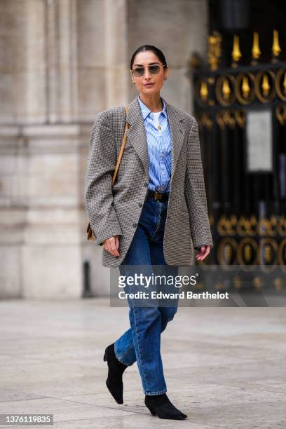 Geraldine Boublil wears gold earrings, a blue and white striped print pattern shirt, a beige and brown houndstooth print pattern oversized blazer...