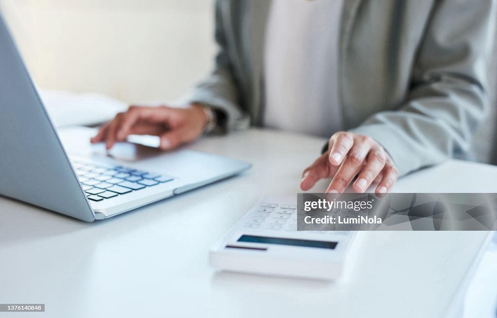 Nahaufnahme einer nicht erkennbaren Geschäftsfrau mit Taschenrechner und Laptop in einem Büro