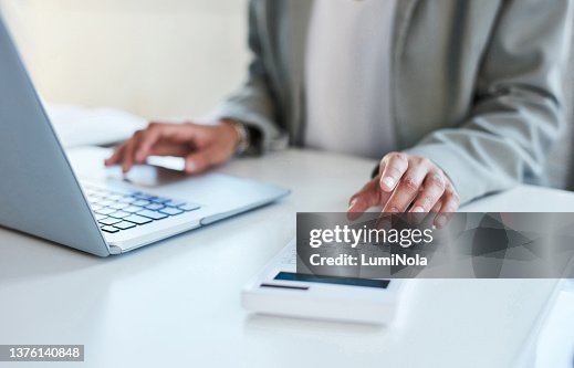 Nahaufnahme einer nicht erkennbaren Geschäftsfrau mit Taschenrechner und Laptop in einem Büro Nahaufnahme einer nicht erkennbaren Geschäftsfrau mit Taschenrechner und Laptop in einem Büro