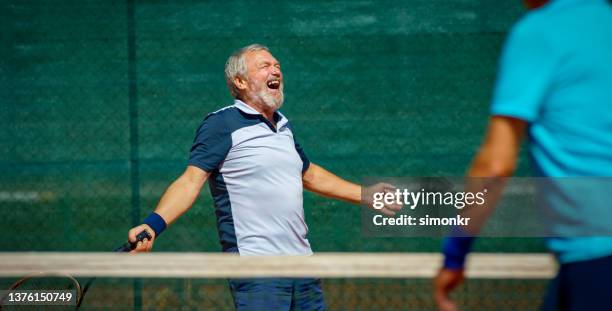 senior man celebrating on tennis court - senior tennis stock pictures, royalty-free photos & images