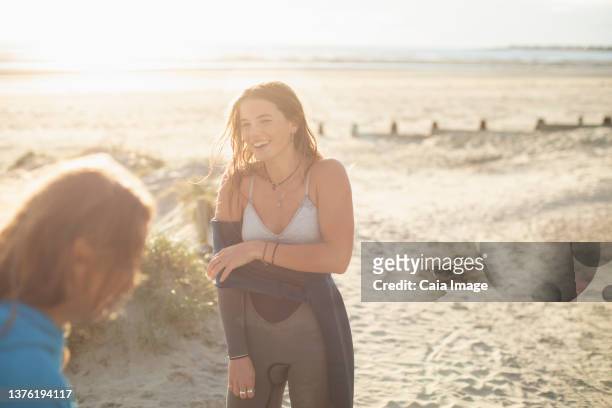 happy young female surfer removing wet suit on sunny beach - soft focus stock pictures, royalty-free photos & images
