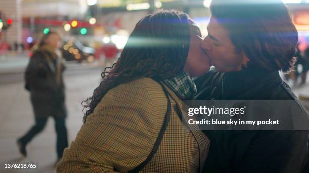 a young couple kissing at night on the city street - beso en la boca fotografías e imágenes de stock