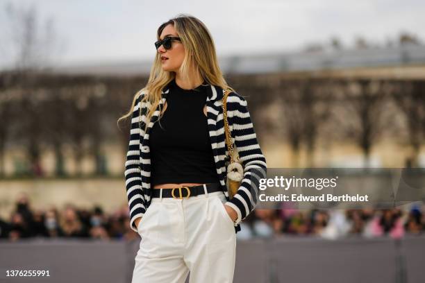 Guest wears black sunglasses from Ray Ban, a black wool tank-top, a black and white striped print pattern wool cardigan, a brown suede and white...