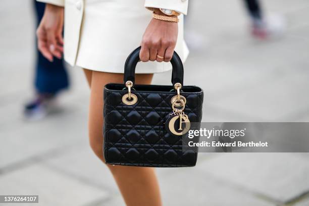 Guest wears a white latte cropped jacket, a matching white latte buttoned short skirt, a black shiny leather Lady D-Lite hand bag from Dior, a gold...