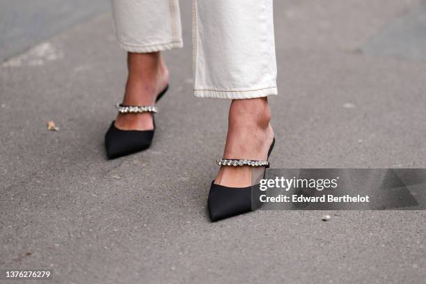 Guest wears white denim cigarette pants, black satin pointed pumps heels shoes with rhinestones strap, outside Victoria/Tomas, during Paris Fashion...