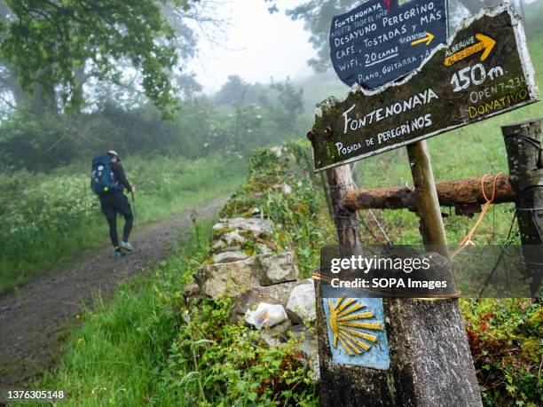 Pilgrim is seen passing by several marks that are pointing places to sleep and eat on the Camino de Santiago pilgrimage route. The Camino de Santiago...
