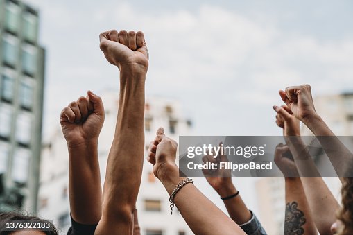Menschen mit erhobenen Fäusten bei einer Demonstration in der Stadt Menschen mit erhobenen Fäusten bei einer Demonstration in der Stadt