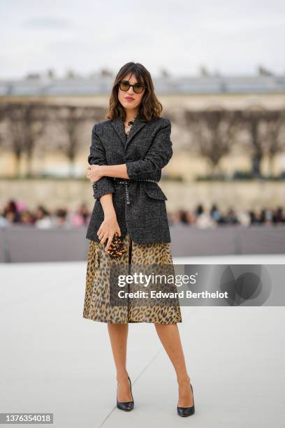 Jeanne Damas wears black sunglasses, a gold chain necklace, a gray wool blazer jacket, a beige and brown leopard print pattern shirt dress, a black...