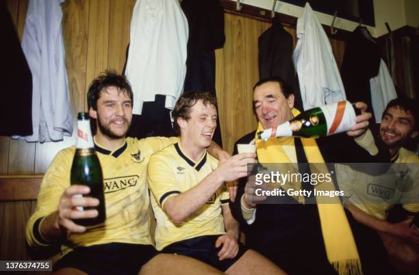 Oxford players Jeremy Charles and Les Phillips of Oxford United celebrate with owner Robert Maxwell who pours the champagne in the dressing room...
