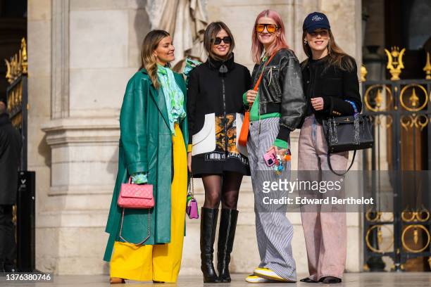 Guest wears gold earrings, a pale blue and green print pattern ruffled shirt, a green shiny leather long coat, high waist yellow large pants, a pink...