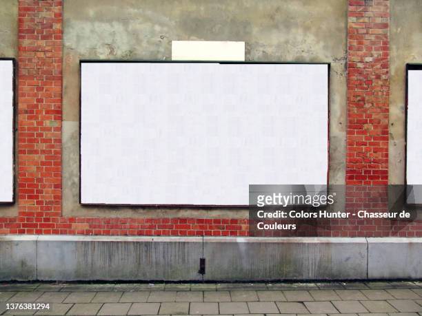 an empty billboard on a weathered wall and sidewalk in brussels - placard stock-fotos und bilder