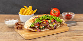 Döner Kebab Doner Kebap slice fast food in flatbread with French Fries on a wooden board panorama