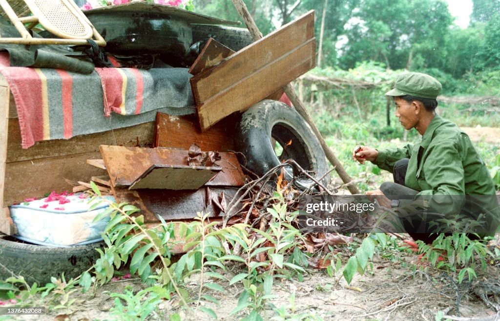 A Khmer Rouge fighter lights the pyre beneath the coffin of his... News ...
