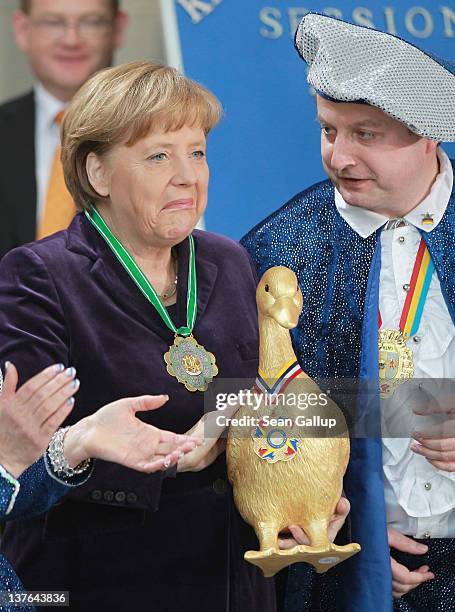 German Chancellor Angela Merkel reacts after receiving an effigy of a golden goose from a Carnical Prince at a reception of German Carnival delegates...