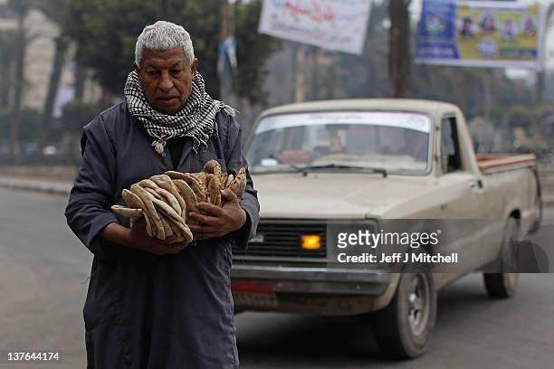 Man walks with his bread bought from Magra El-Oyoun market on January 24, 2012 in Cairo, Egypt. The country is struggling with falling tourism...