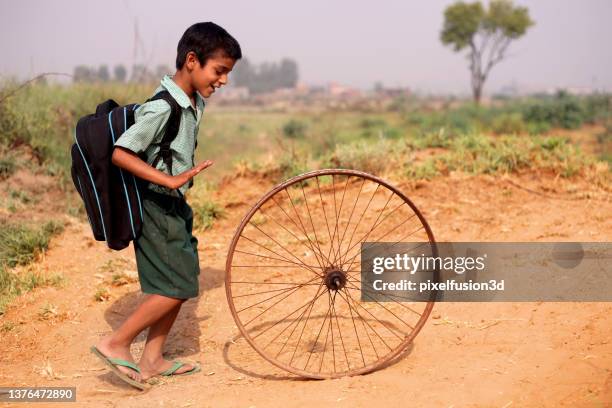 poor child running bicycle tyre on country road - rural scene stock pictures, royalty-free photos & images