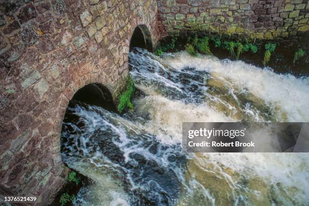 wastewater from large sewage treatement plant flowing directly into a river. - águas residuais imagens e fotografias de stock