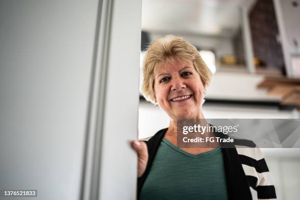 portrait of a senior opening door at home - só uma mulher idosa imagens e fotografias de stock