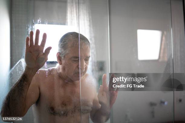 sad senior man taking a shower - bathroom senior stock pictures, royalty-free photos & images