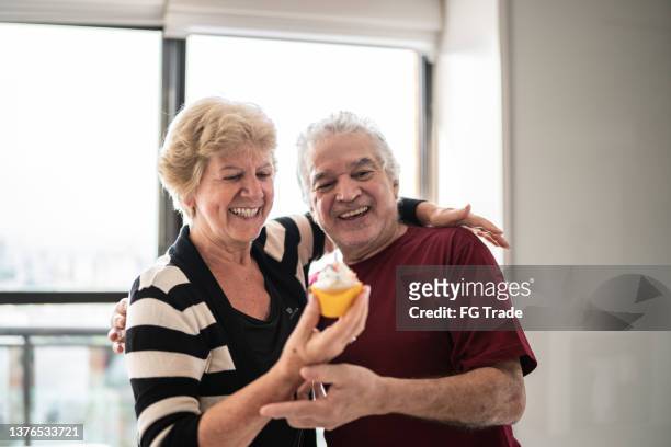 senior couple celebrating with a cupcake - proud old man stock pictures, royalty-free photos & images