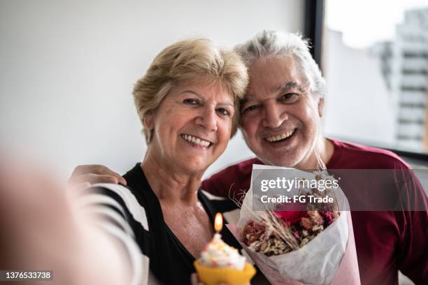 pov of a senior couple taking a selfie with cupcake and a bouquet - happy anniversary stock pictures, royalty-free photos & images