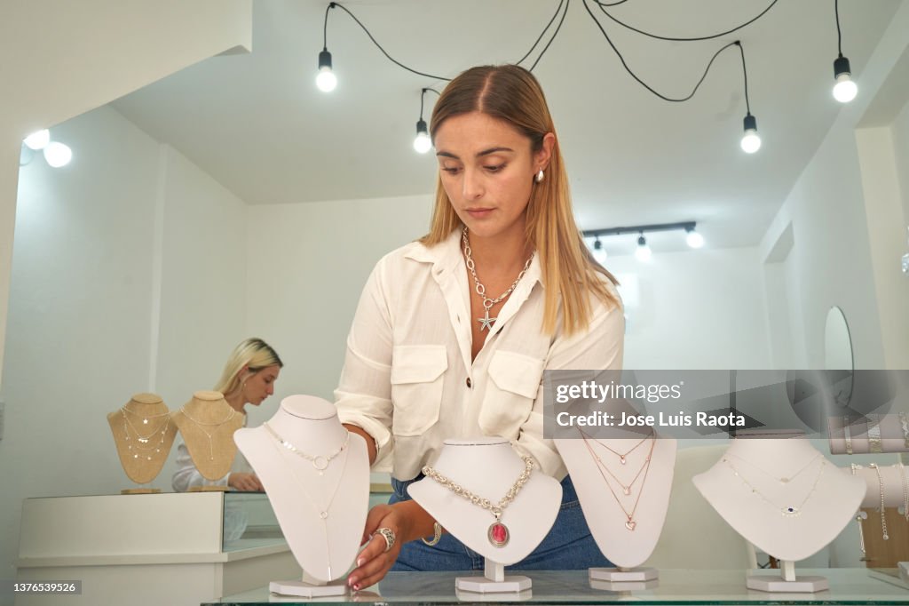 She is holding a necklace and presenting her jewelry brand.